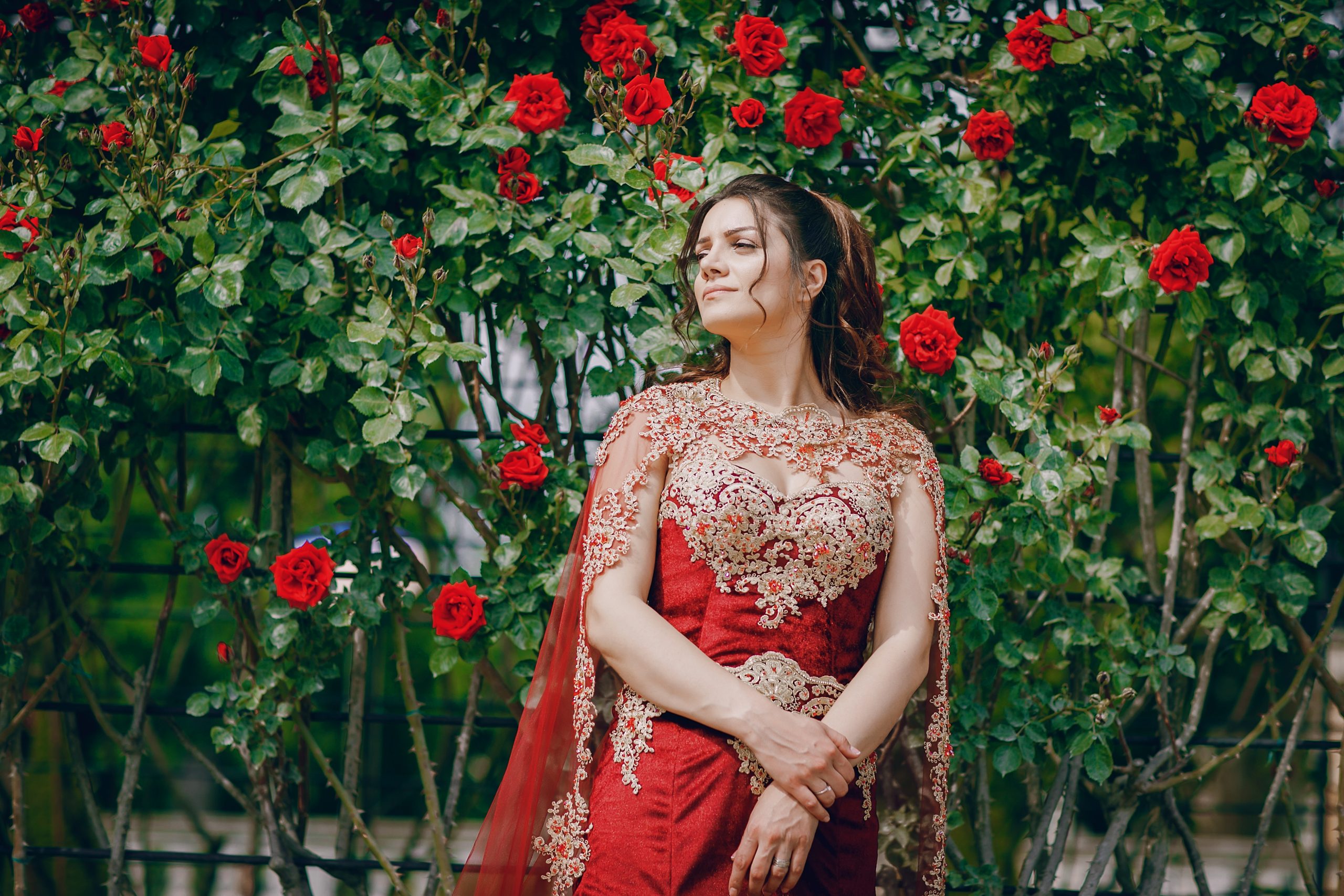 A beautiful Turkish girl in a long red dress walks in the summer old city