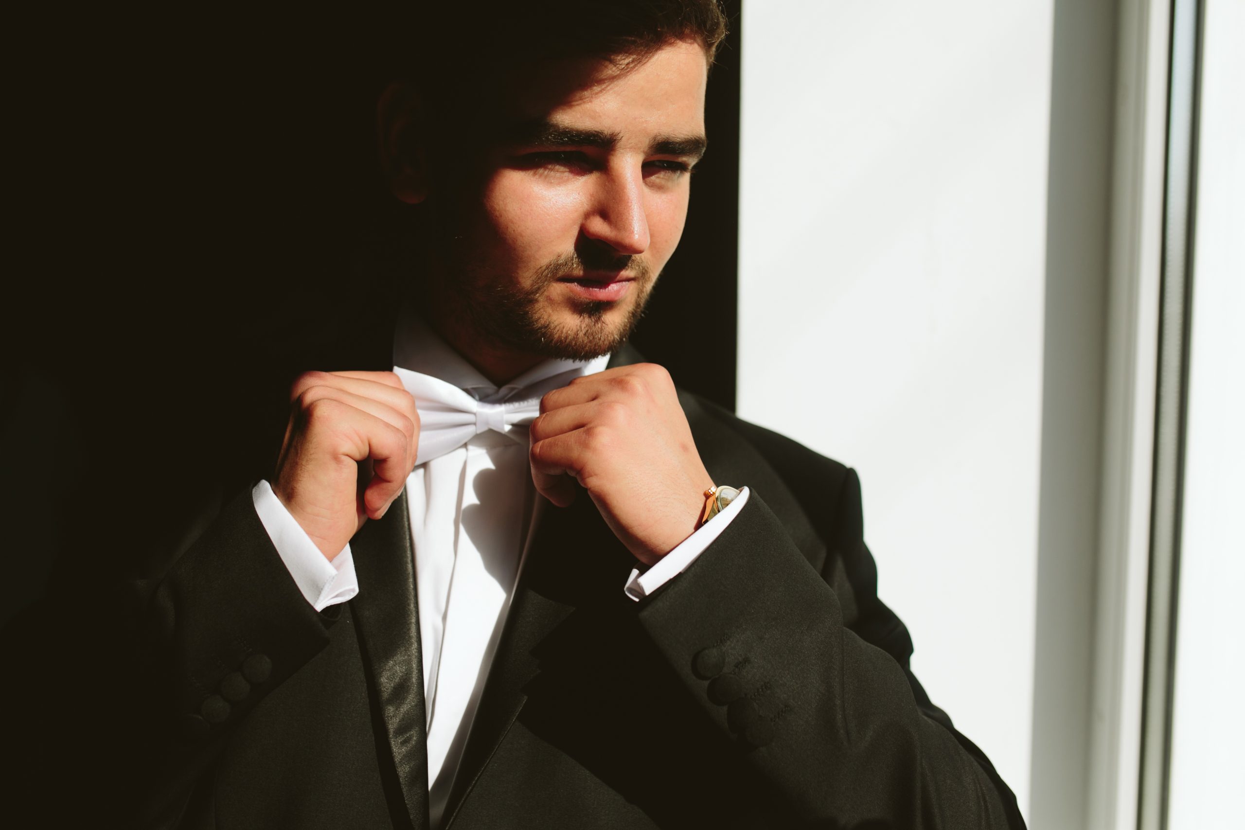 solid brunette groom in  black suit indoor sunlight